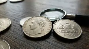 Monete italiane da 500 lire d’argento con lente d’ingrandimento su un tavolo, dettaglio numismatico